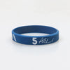A blue silicone wristband with the number 5 and a signature on the front.