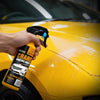 A hand sprays Man Ceramic Coating Agent on a yellow car's hood.