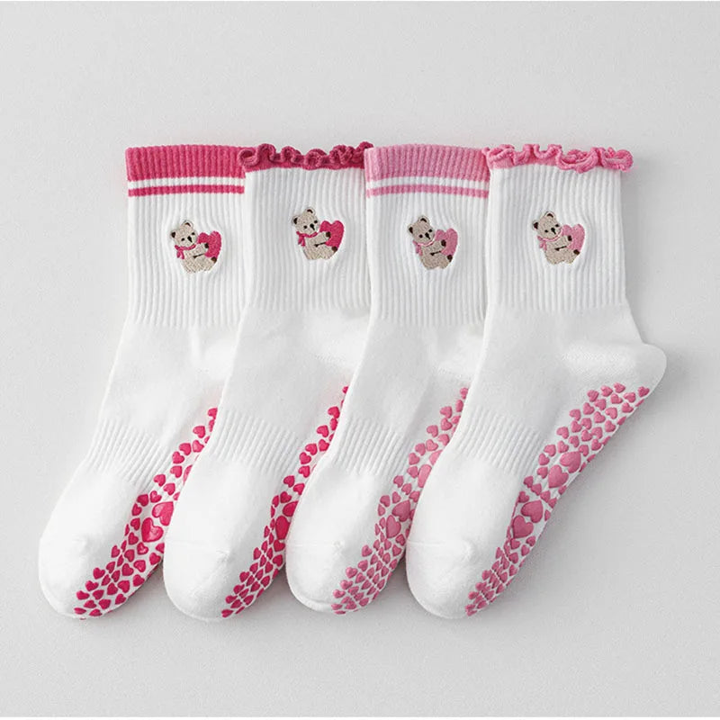 Un ensemble de chaussettes de yoga blanches avec broderies roses et adhérence antidérapante à l'orte.