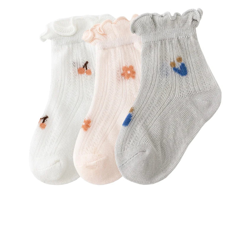 A pack of three thin summer casual baby socks in white, pink, and gray with small floral or abstract designs.
