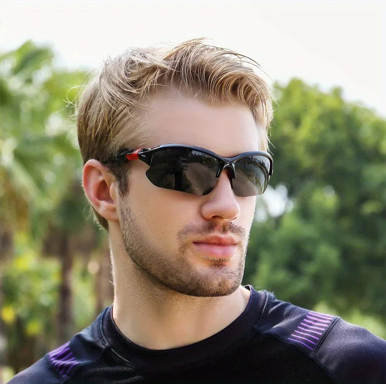 A young man wearing black polarized sport sunglasses outdoors against a blurred green background.