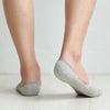 Une paire de chaussettes invisibles en silicone gris respirantes, portées pieds nus.
