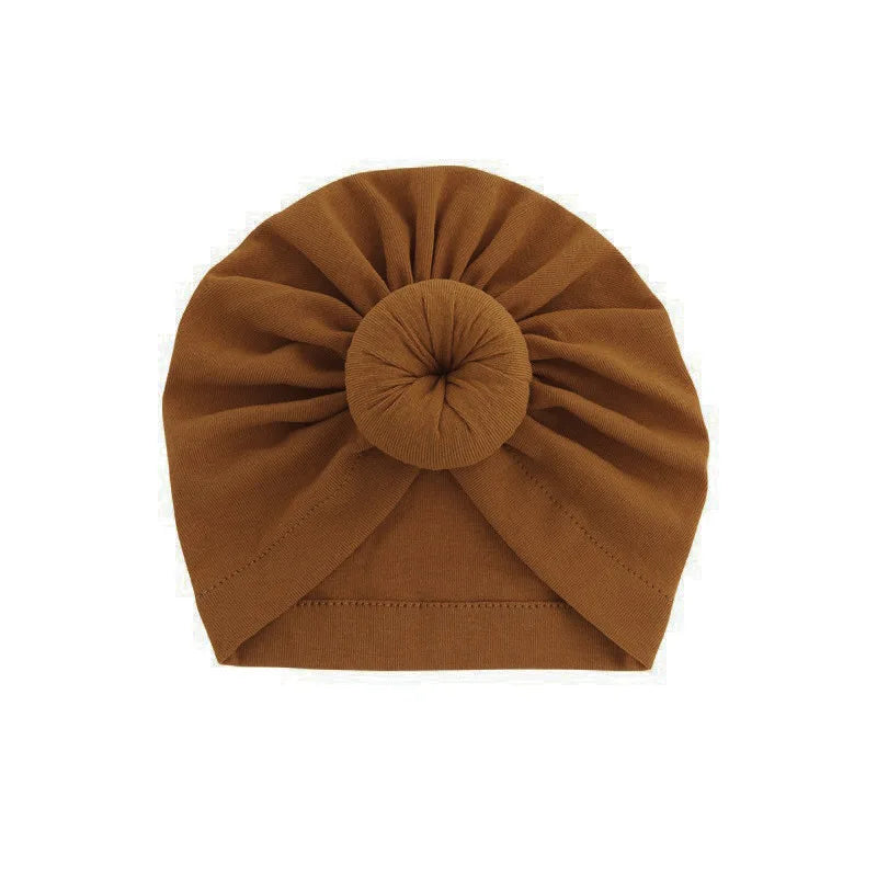 Einesdunkles braunes Baumwoll-Babyturban mit zusammengebundener Spitze und Rundknoten-Detail.