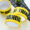 A roll of yellow industrial safety warning tape placed next to a black keyboard and a small cactus.
