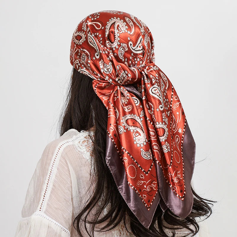 A woman is shown from the back wearing a vibrant orange and maroon paisley silk shawl scarf.