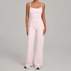 A woman wearing a light pink high-waist yoga and fitness tracksuit set consisting of a tank top and matching trousers.