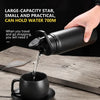 A hand pours water from a black portable water bottle into a black mug on a wooden surface.