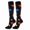 A pair of black compression elastic socks featuring colorful splatter patterns in orange, blue, and green.