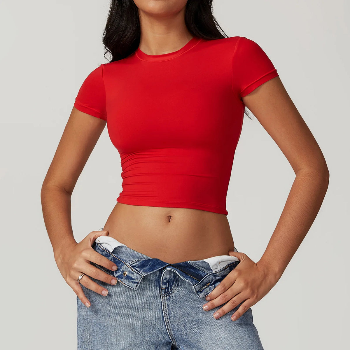 Una mujer vistiendo una camiseta y jeans de yoga y fitness rojos de secado rápido.