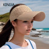 A woman wearing a beige breathable anti-UV adjustable sun hat while standing on a beach.