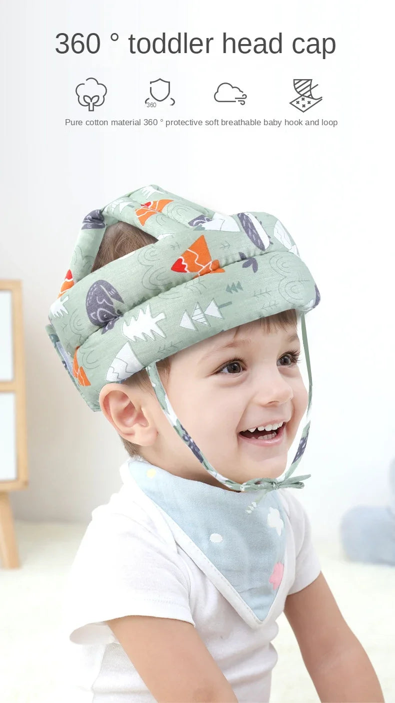 A toddler is wearing a light green and white patterned 360 degree head cap made of pure cotton for protection.