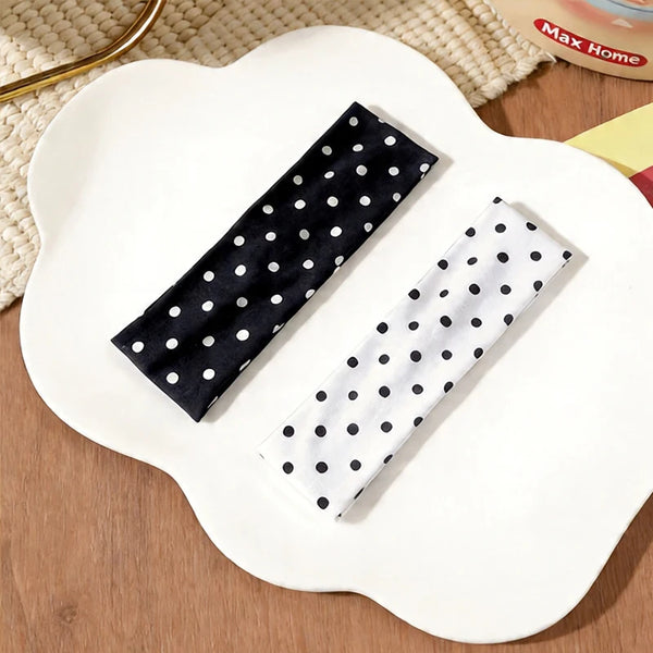 Eine schwarz-weiße Polka-Dot-Stoff-Haube für Yoga und Sport auf einem weißen Teller.