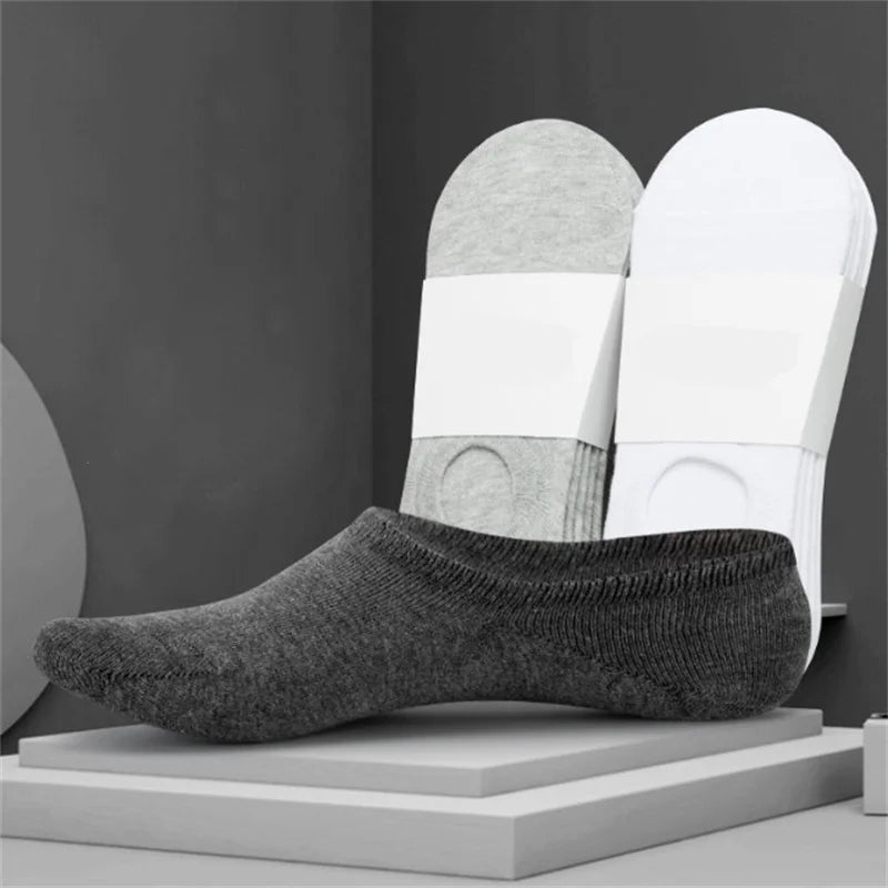 A pair of gray invisible silicone no-show boat socks displayed next to white socks on a gray background.