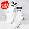 A pair of white crew socks with black lettering that reads NEW YORK, displayed on a textured background.