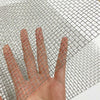 Une main presse à travers une grille de fils en acier inoxydable 304 robuste.