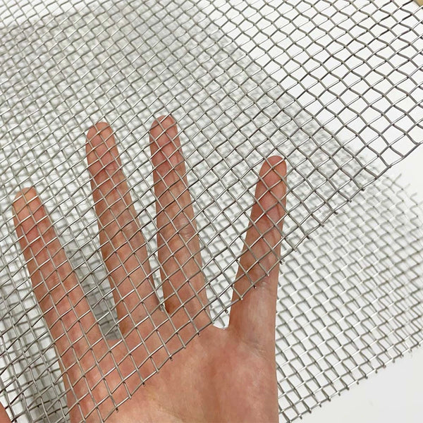 Una mano empujando a través de una malla de alambre de acero inoxidable 304 de alta resistencia.