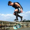 A muscular man wearing compression socks is performing a physical exercise outdoors.