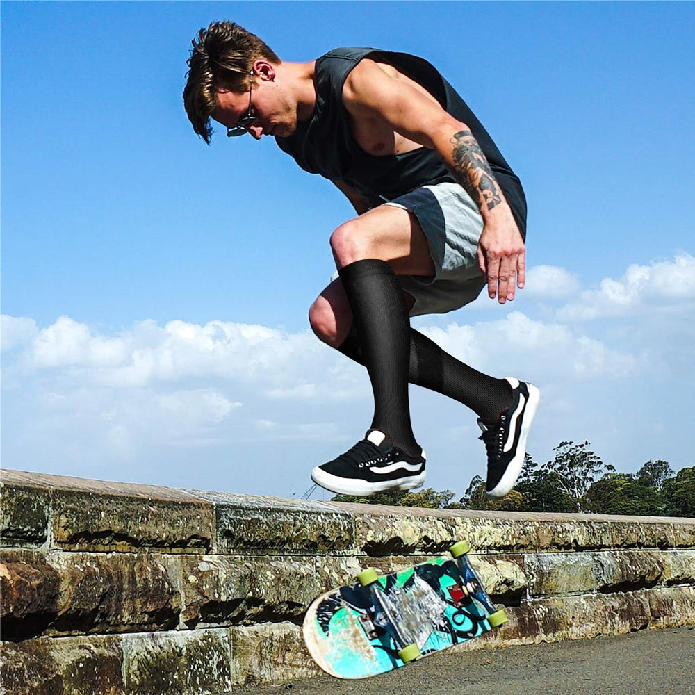 A muscular man wearing compression socks is performing a physical exercise outdoors.