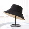 A black double-sided wide brim bucket hat displayed on a stand.