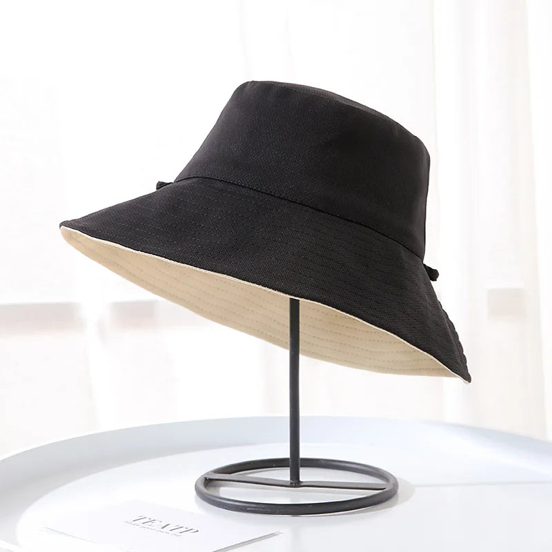 A black double-sided wide brim bucket hat displayed on a stand.