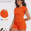A woman models an orange sports casual tracksuit consisting of a short-sleeved top and matching shorts.