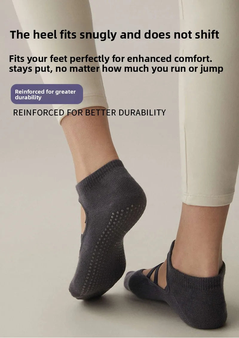 A close-up of a person wearing grey crisscross strap yoga socks on their feet.
