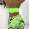 A model shows a bright neon green floral print two-piece high-waist bikini set from the back view.