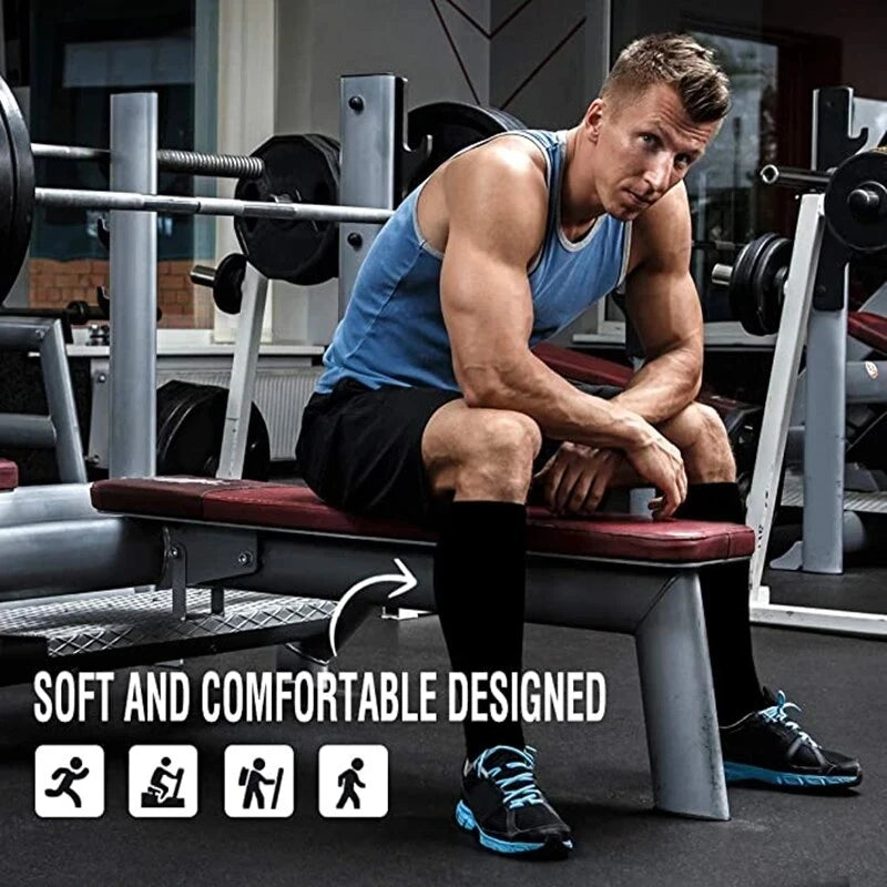 A muscular man wearing black knee-high stockings is sitting on a weight bench in a gym setting.