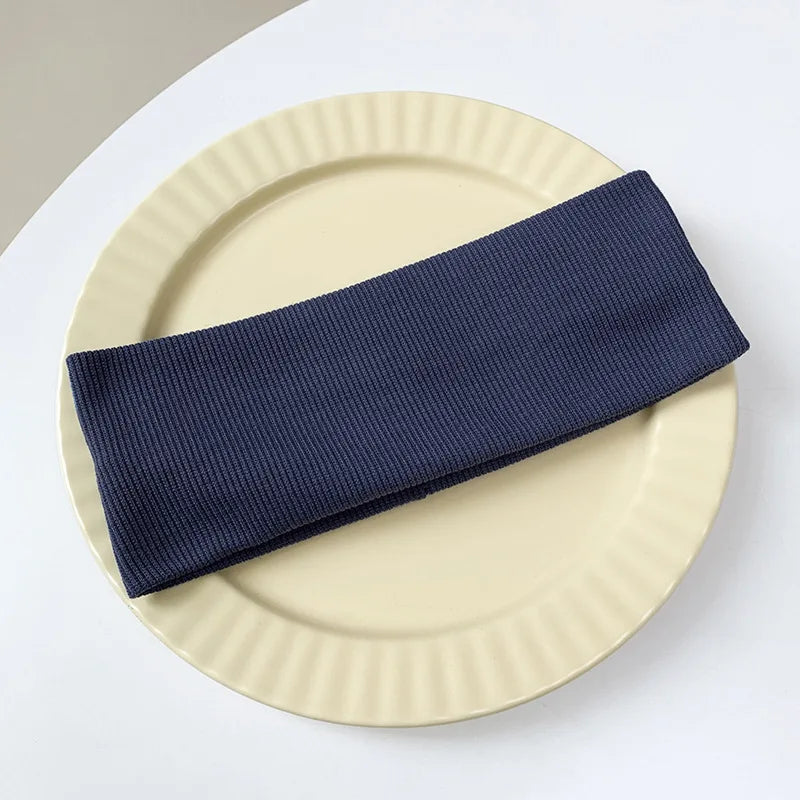 A navy blue elastic hairband is placed diagonally across a light beige plate.