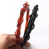 Un set de accesorios para clips y bandas de pelo con flequillo doble naranja y negro, sostenidos en una mano.