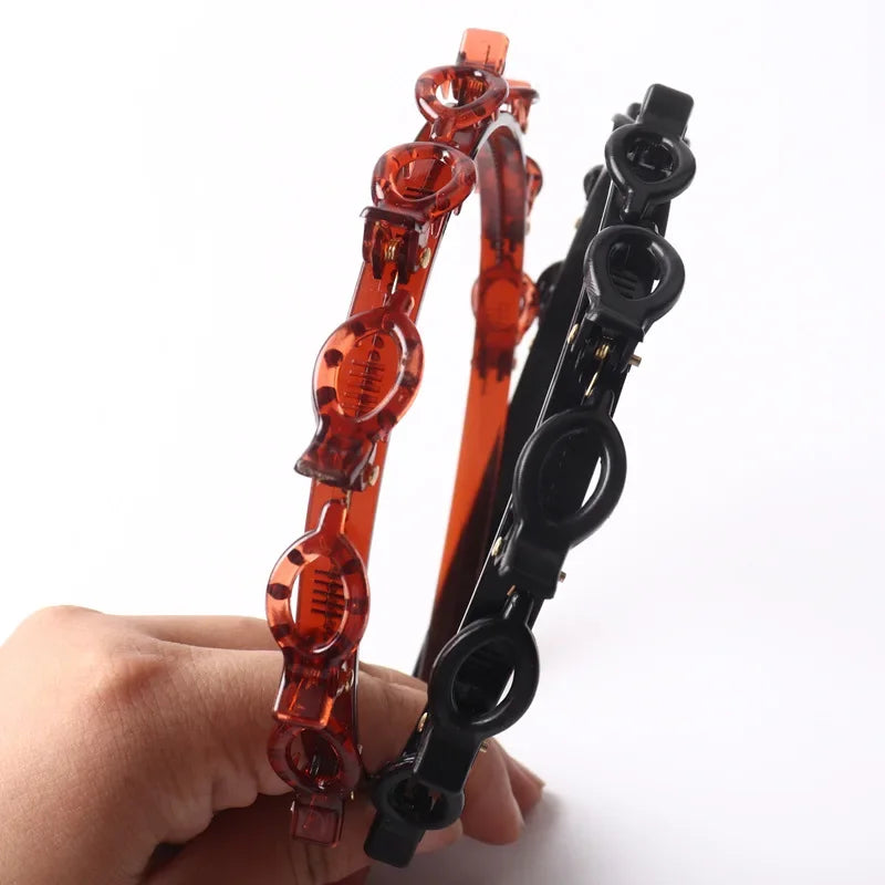 Un set de accesorios para clips y bandas de pelo con flequillo doble naranja y negro, sostenidos en una mano.
