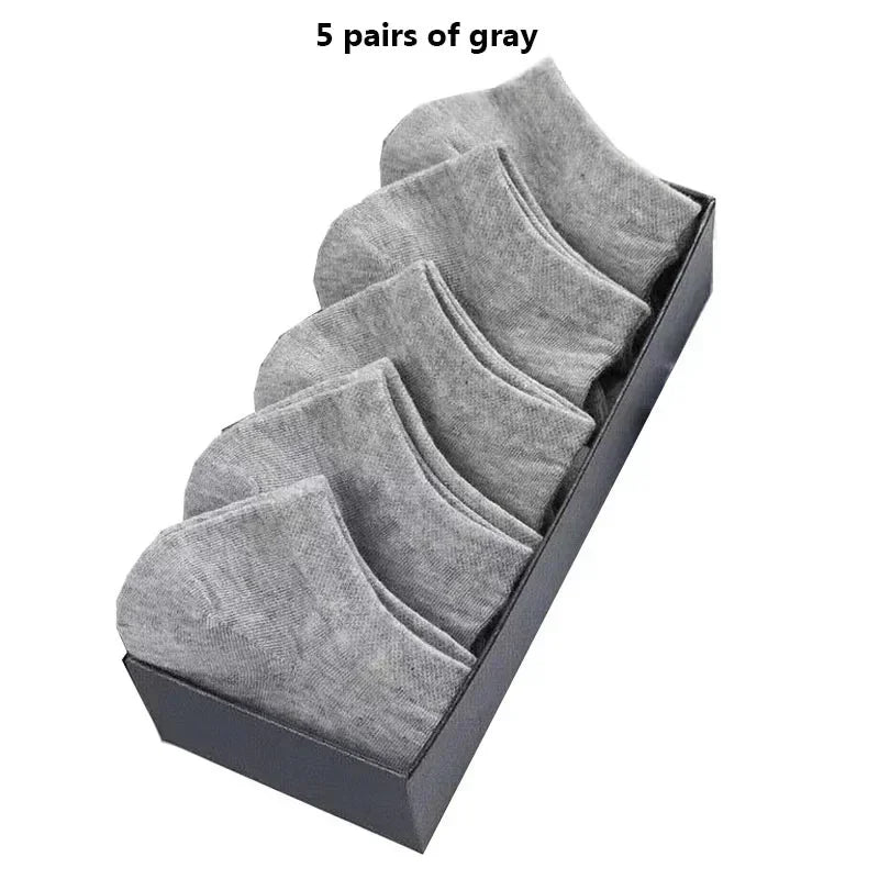 Cinco pares de calcetines de algodón gris transpirables para el tobillo exhibidos en una caja oscura.