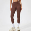 Model in brown seamless high-waist yoga leggings with white socks and light athletic shoes.