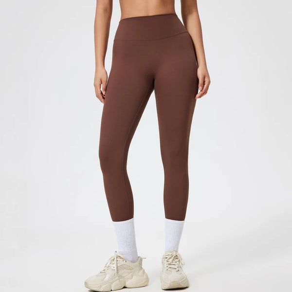 Model in brown seamless high-waist yoga leggings with white socks and light athletic shoes.