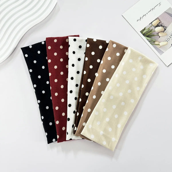A collection of polka dot elastic yoga headbands in various colors including black, maroon, white, and brown.