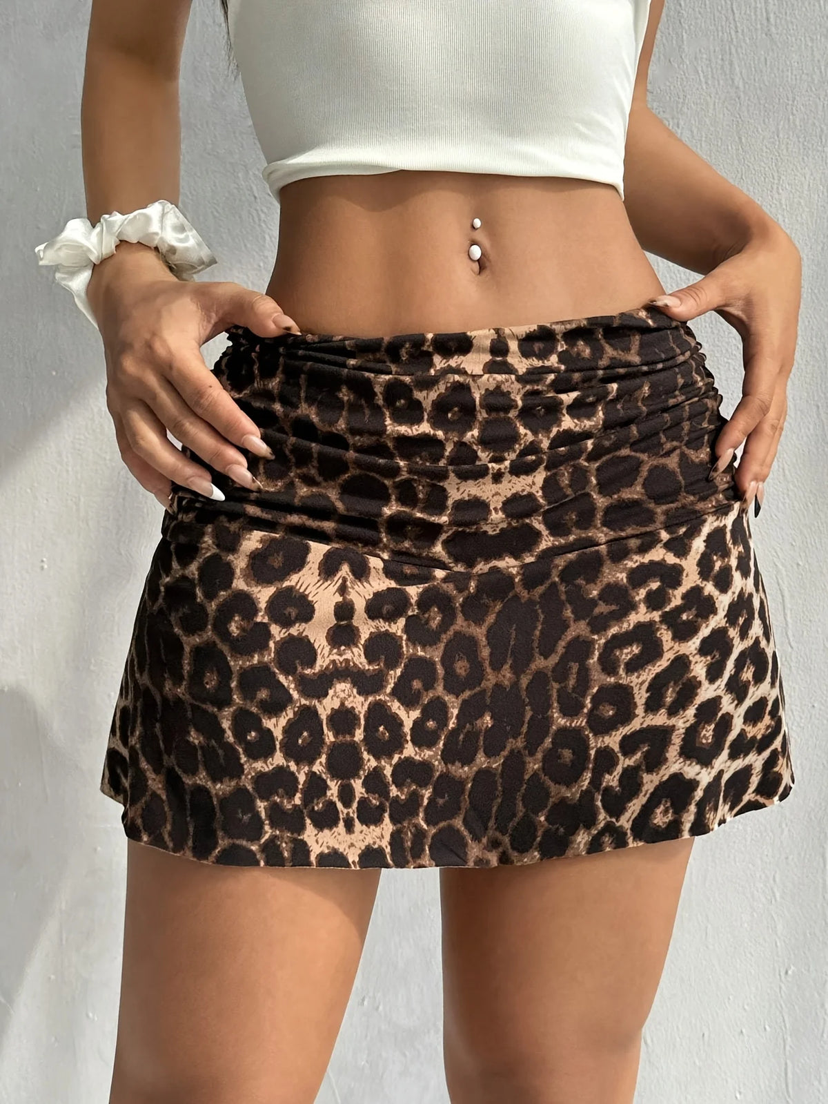 A woman models a brown and black leopard print casual mini skirt with a white crop top.