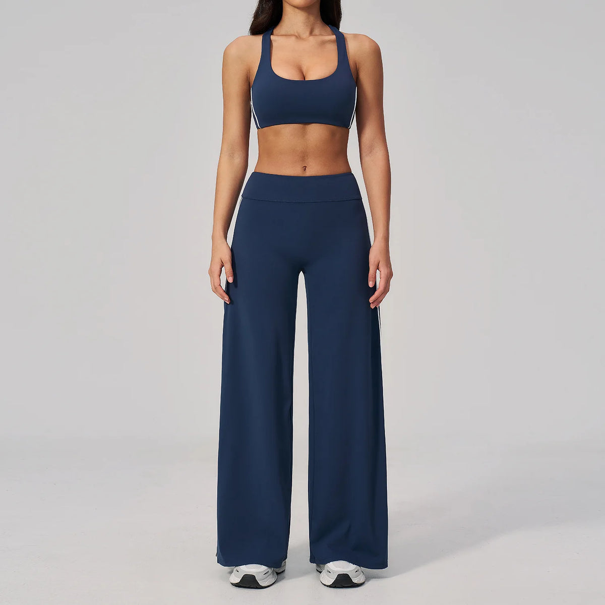 A woman wearing a navy blue two-piece yoga and sports tracksuit set consisting of a cropped top and full-length pants.