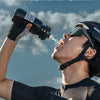A man is drinking from a black sports water bottle outdoors, enjoying hydration during exercise.