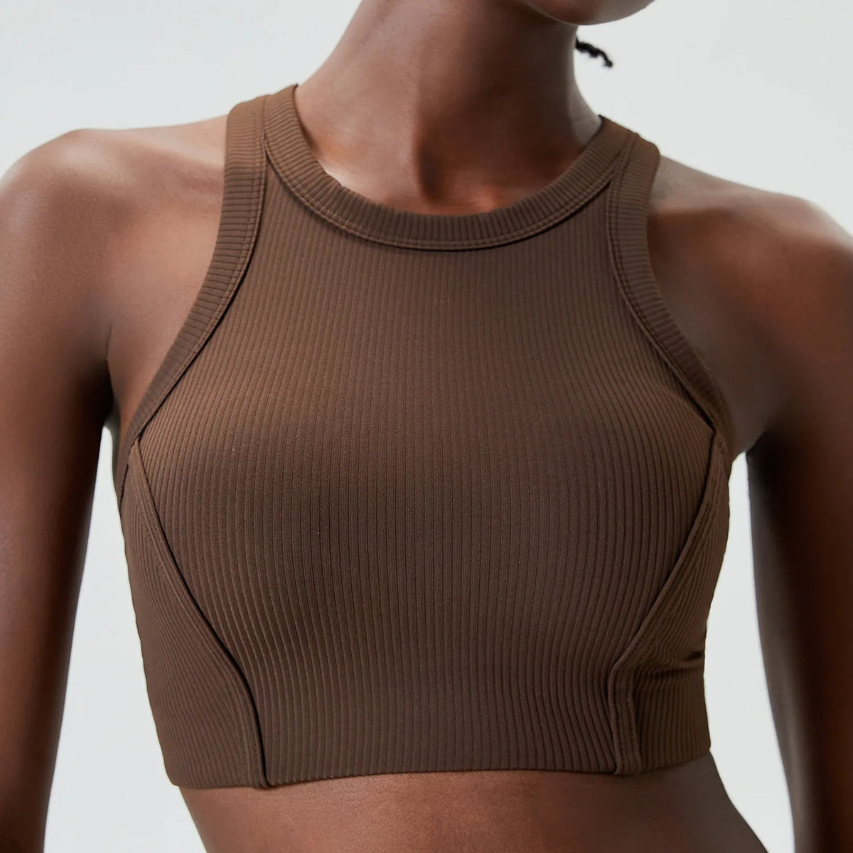 A model wearing a brown ribbed high-impact stretch yoga crop top.
