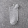 A single light gray ankle sock is displayed against a textured gray background.