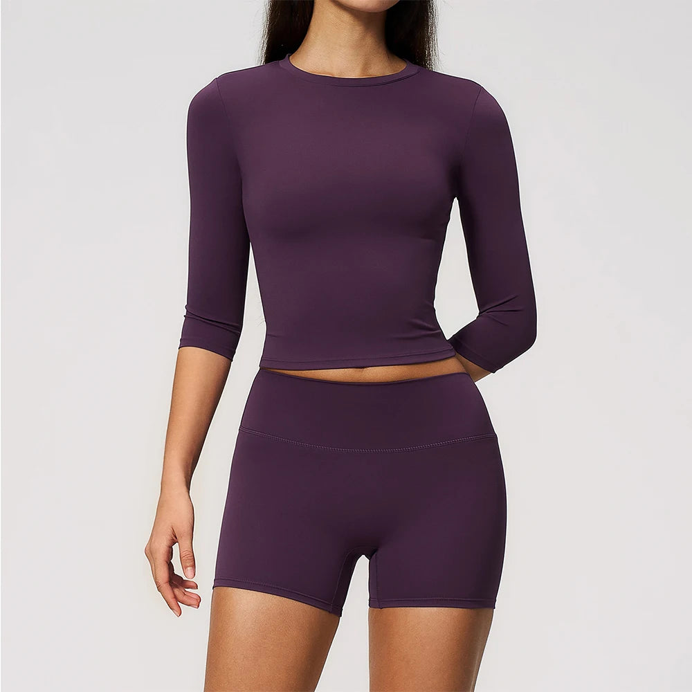 A woman wearing a purple long-sleeved top and matching high-waisted leggings set for yoga and fitness.