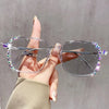 A hand holds a pair of clear photochromic diamond style eyeglasses decorated with sparkling gems.