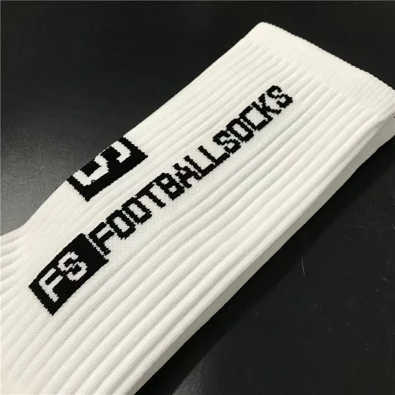 White anti-slip silicone grip football socks shown diagonally on a dark surface.