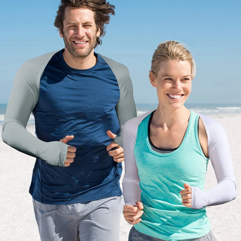 Lächelnder Mann und Frau tragen UV-Schutz-Armwärmer beim Laufen am Strand.