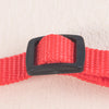 A close-up of a red woven adjustable pet scarf with a black plastic buckle.