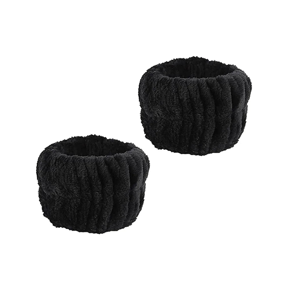 A set of black microfiber spa headband and wristband, rolled into a cylindrical shape.