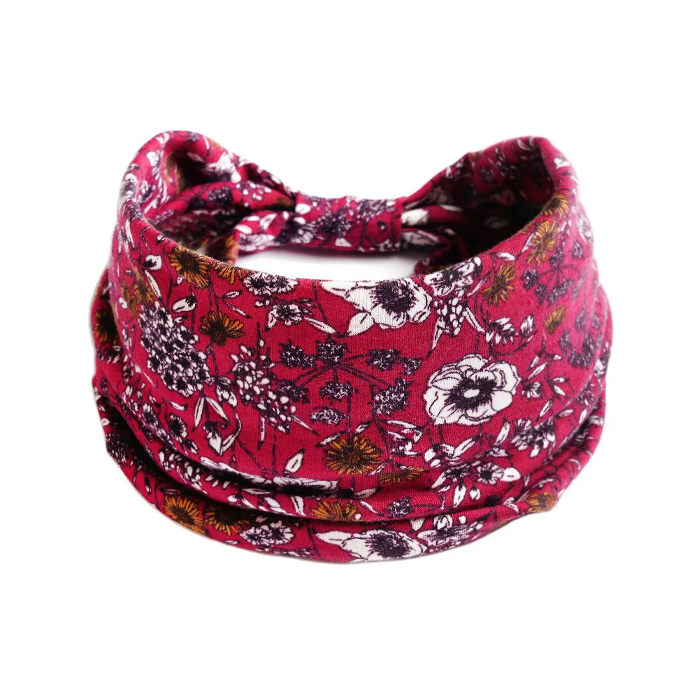 A close-up of a red floral patterned cotton stretch headband tied in a bow.