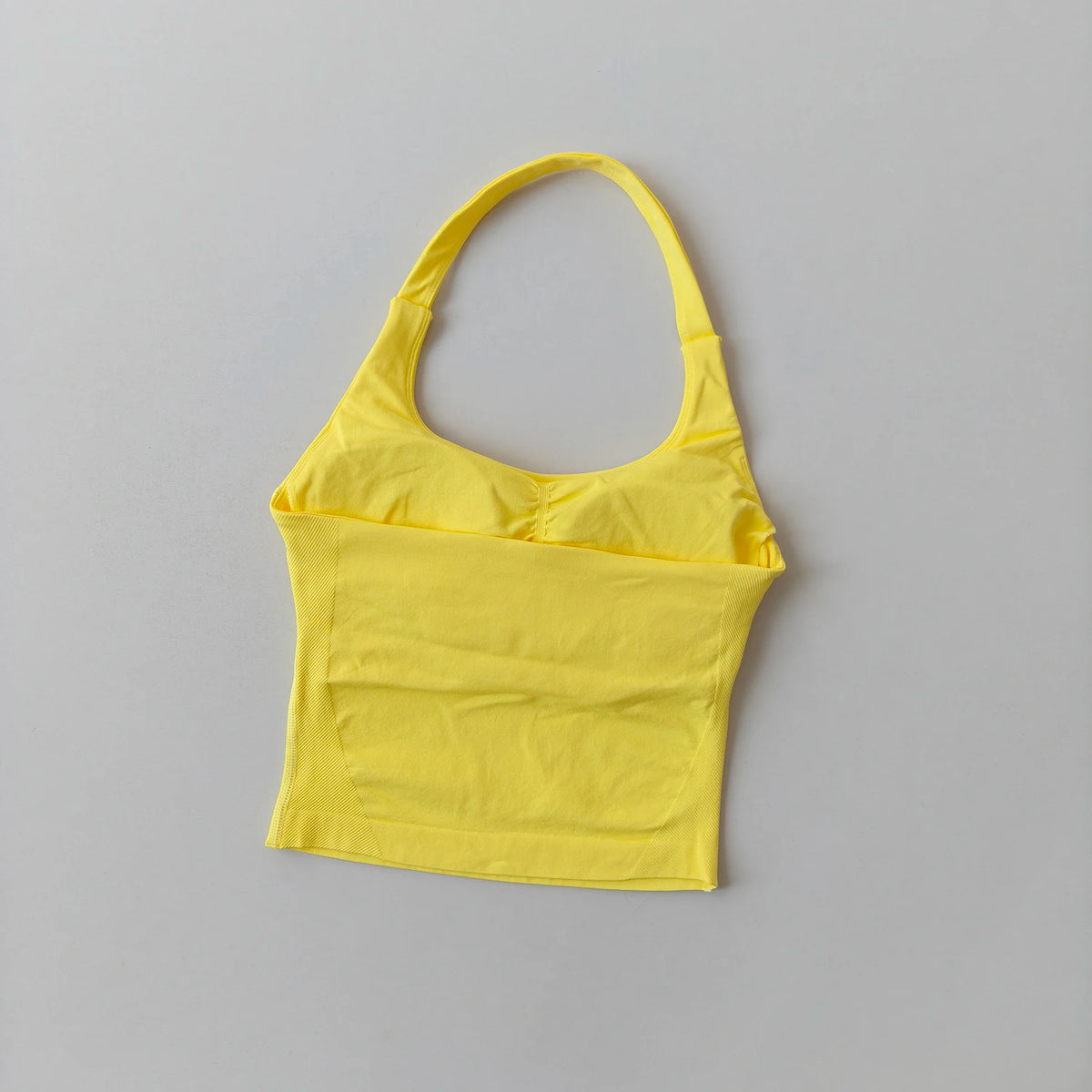 Haut sans coutures jaune vif pour femmes, style col, pour yoga et fitness, sur fond gris clair.