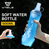 A hand holds a light blue soft water bottle with a clear cap against a dark, leafy background.