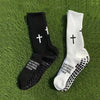A pair of black and white cross printed athletic socks lying on green grass.